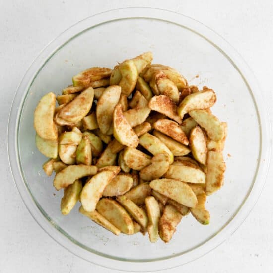 apple slices in a glass bowl on a white background.