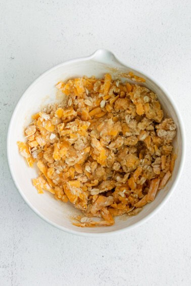 a white bowl filled with shredded cheese and granola.