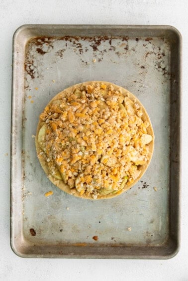 a pie on a baking sheet with toppings on it.
