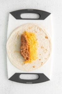 a tortilla with cheese on a cutting board.