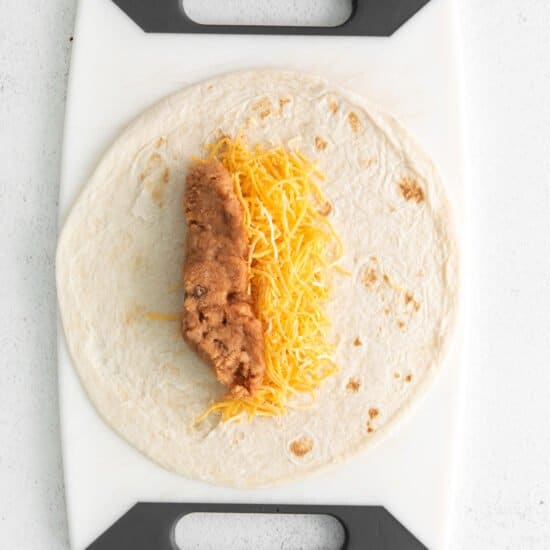 a tortilla with cheese on a cutting board.