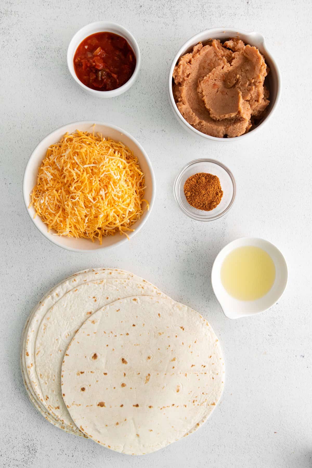 Ingredients for bean and cheese burritos in bowls.