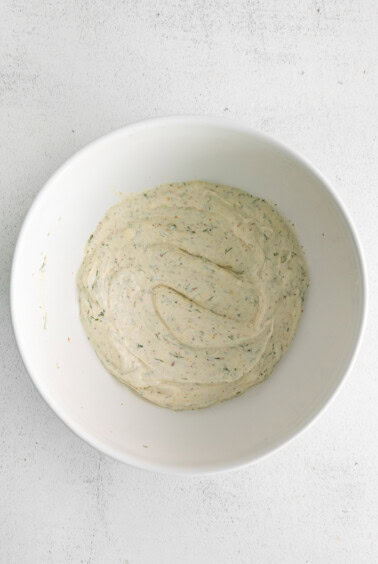 a white bowl with a white sauce on it.