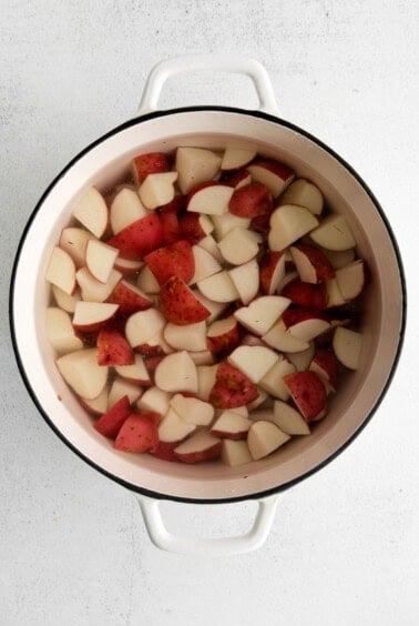 a pot full of sliced potatoes in a white background.