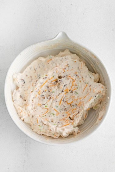 a white bowl with a mixture of cheese and carrots.