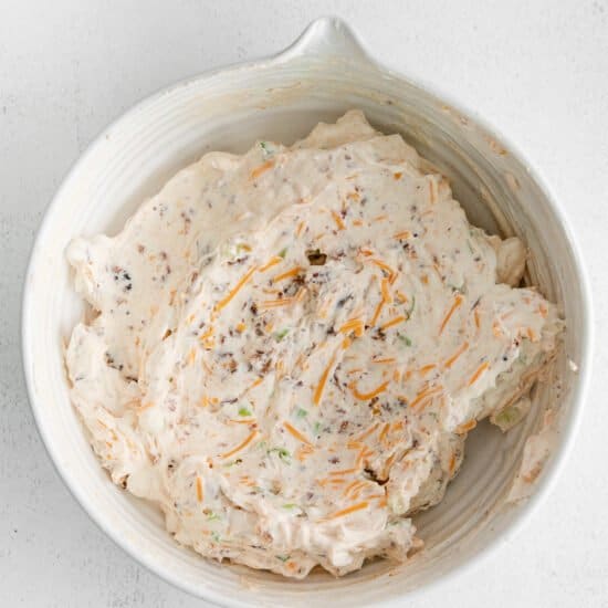 a white bowl with a mixture of cheese and carrots.