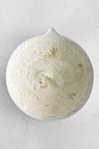 whipped cream in a white bowl on a white surface.
