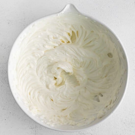 whipped cream in a white bowl on a white surface.