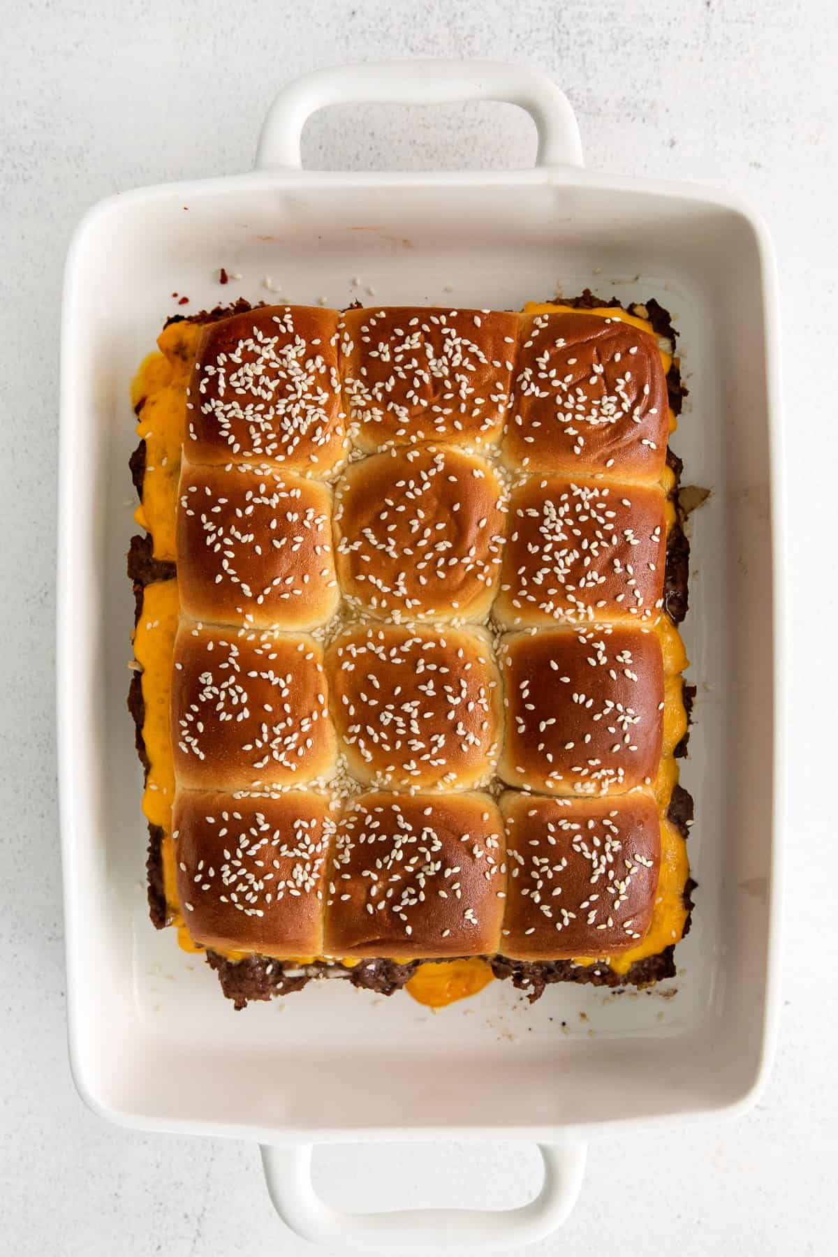 Hawaiian roll cheeseburger sliders in baking dish.