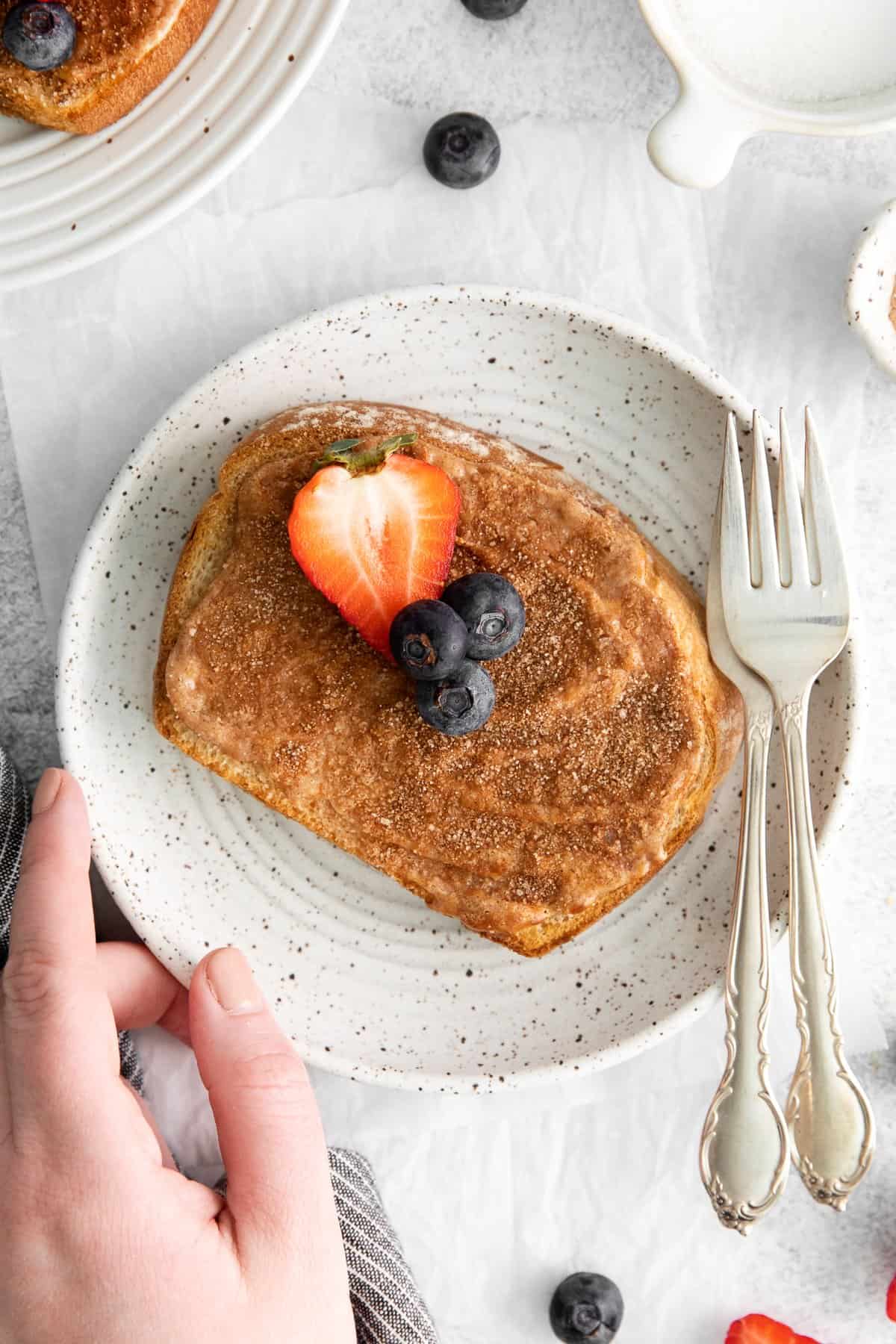 Cream cheese toast with berries on plate.