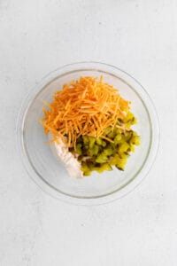 a glass bowl filled with vegetables and cheese.