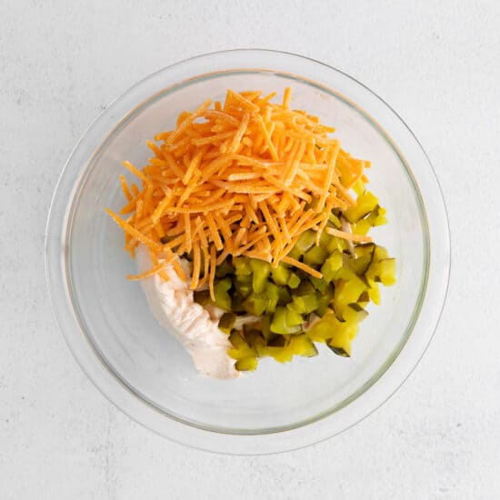 a glass bowl filled with vegetables and cheese.