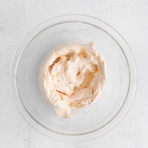 whipped cream in a glass bowl on a white surface.