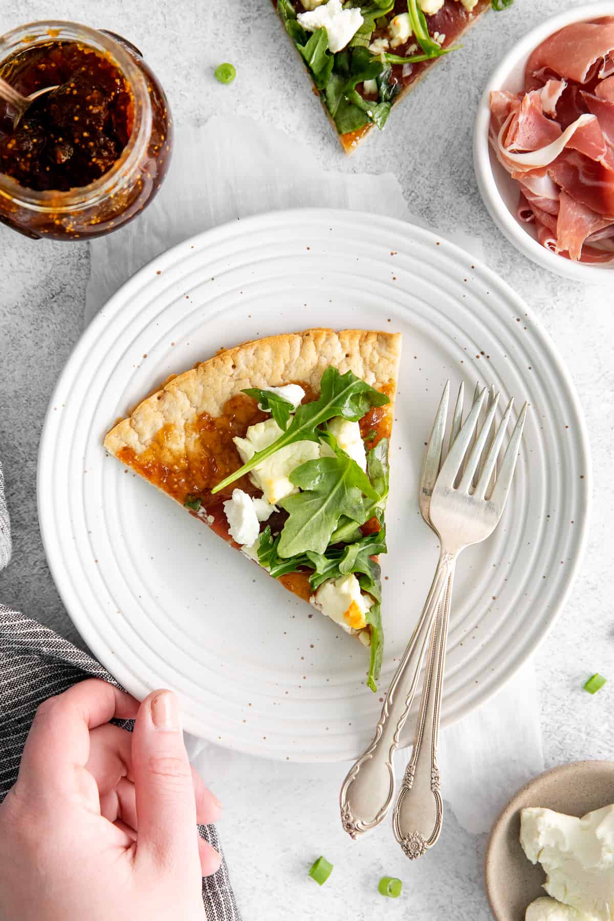 A slice of fig and goat cheese flatbread on a plate with forks.