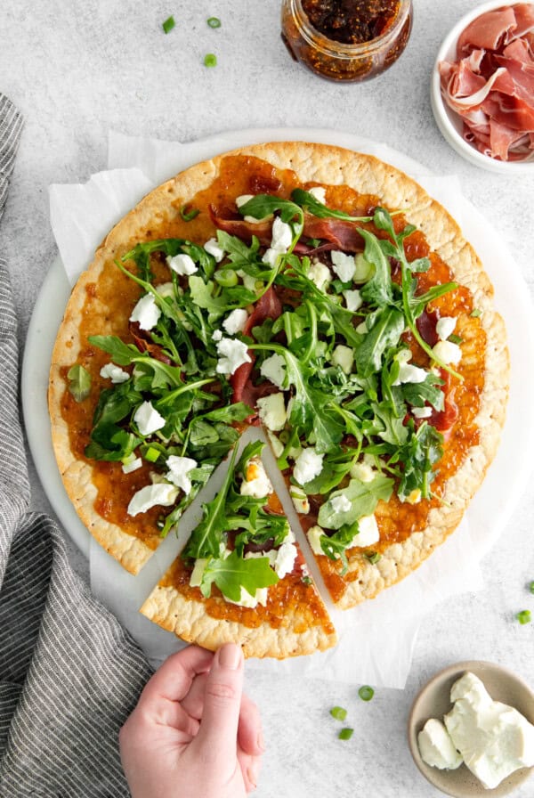 A slice of fig and goat cheese flatbread on a white plate.