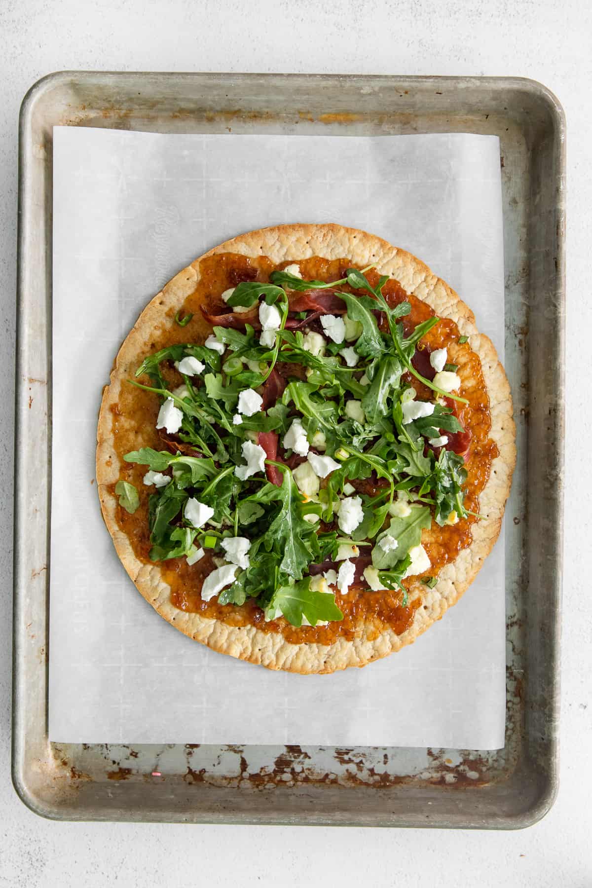 Fit and goat cheese flatbread topped with arugula on a plate.