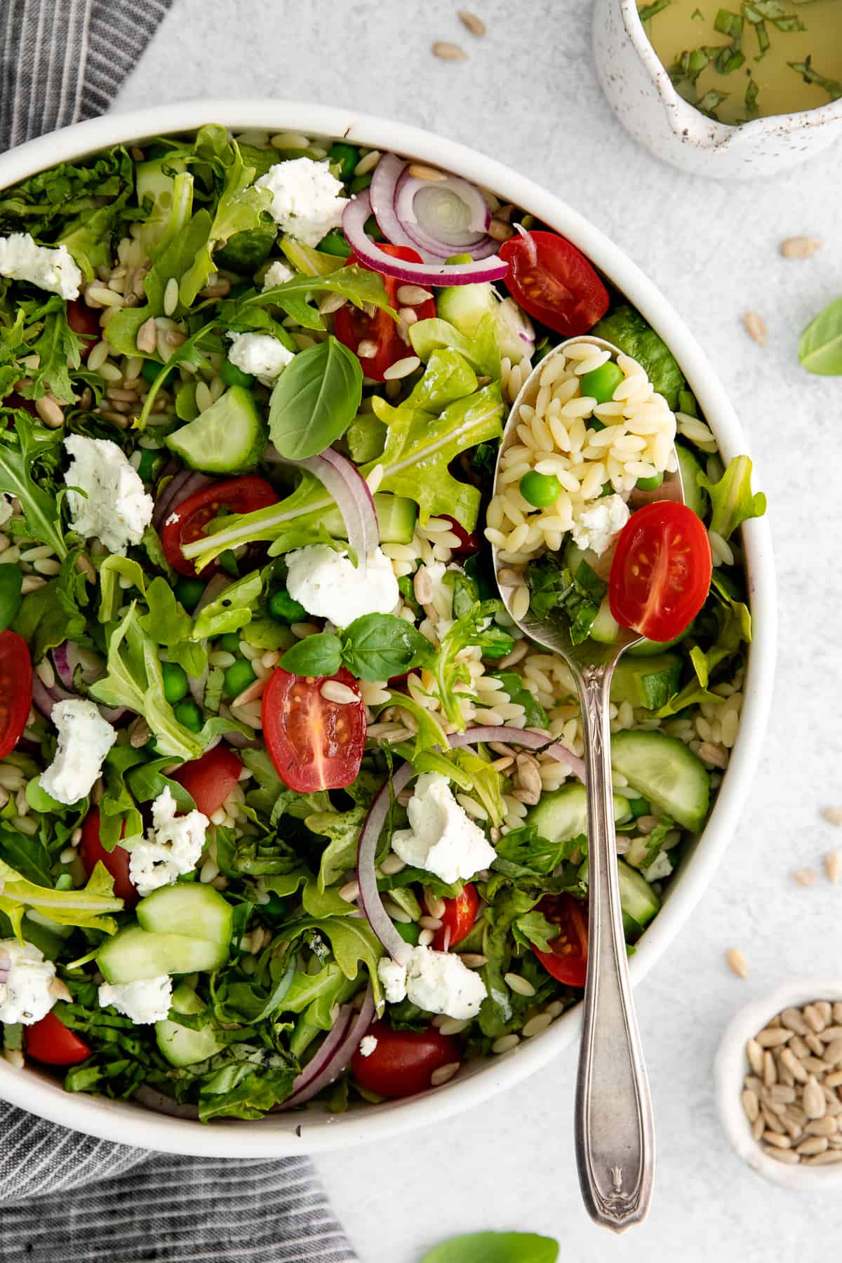 Lemon orzo salad with goat cheese in a serving bowl and a serving spoon. 