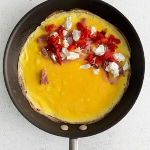 Goat cheese omelette with ingredients in a pan.