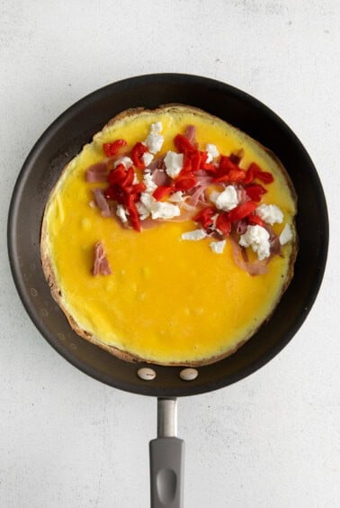 Goat cheese omelette with ingredients in a pan.