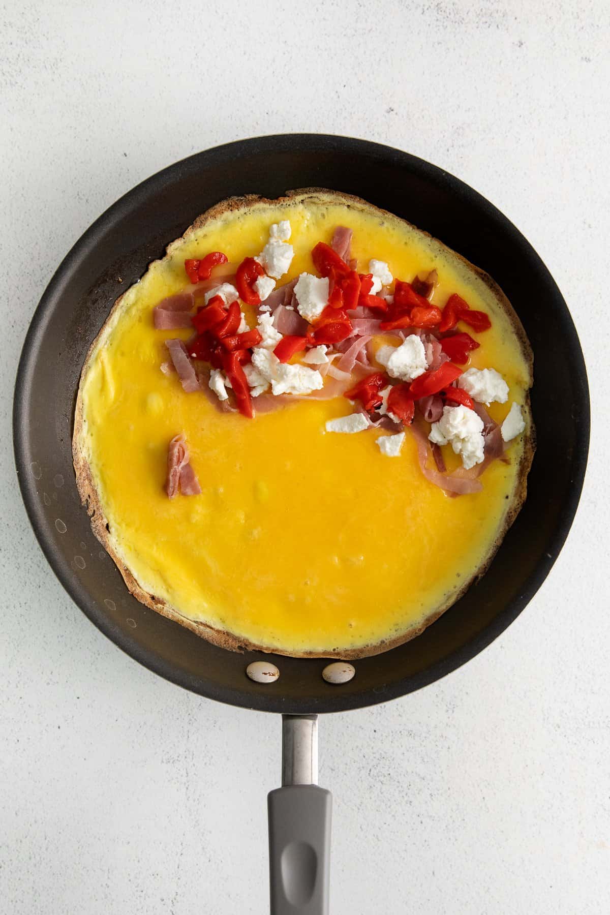 Goat cheese omelette with ingredients in a pan.