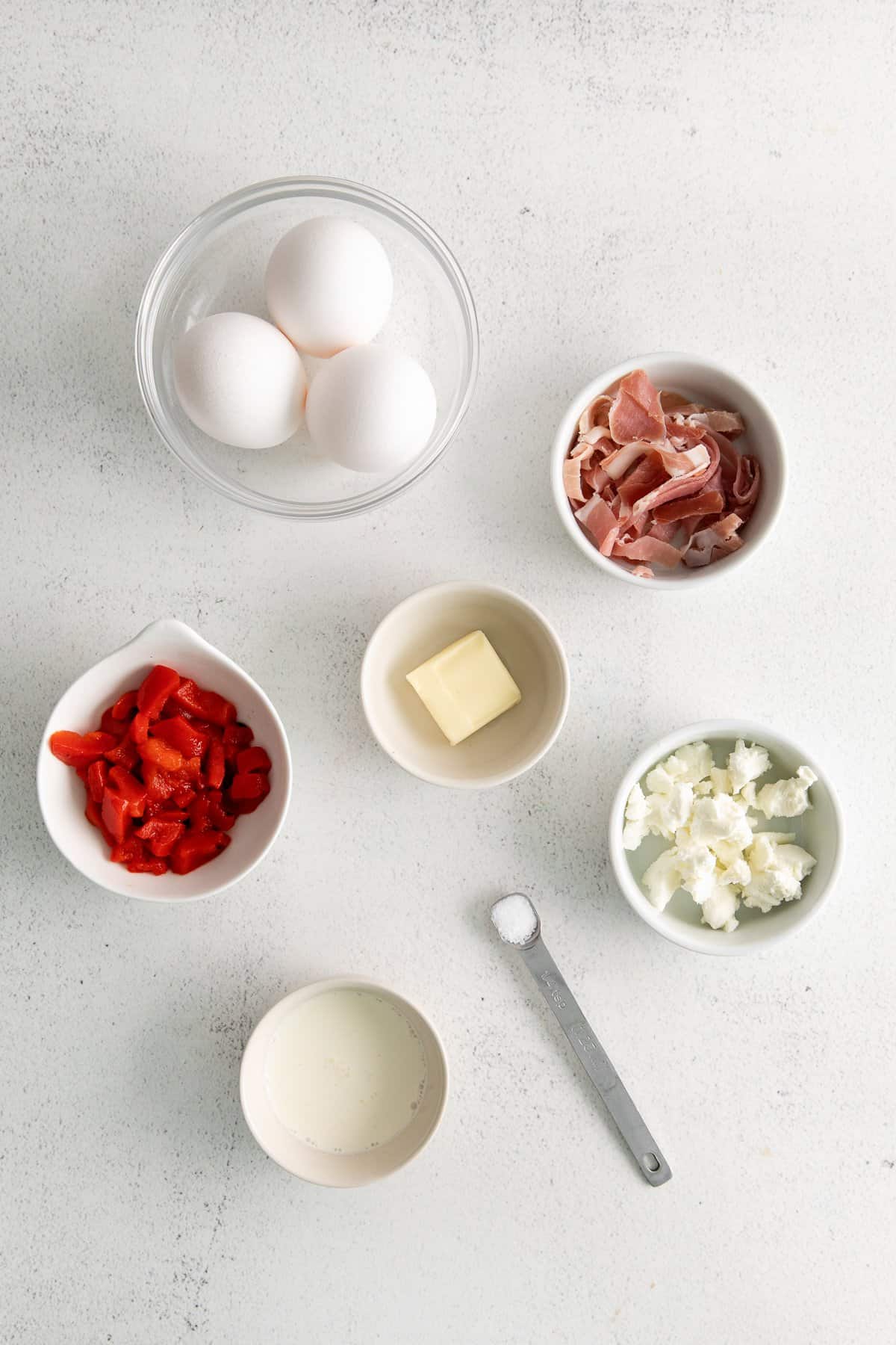 All of the ingredients for a goat cheese omelet in small bowls. 