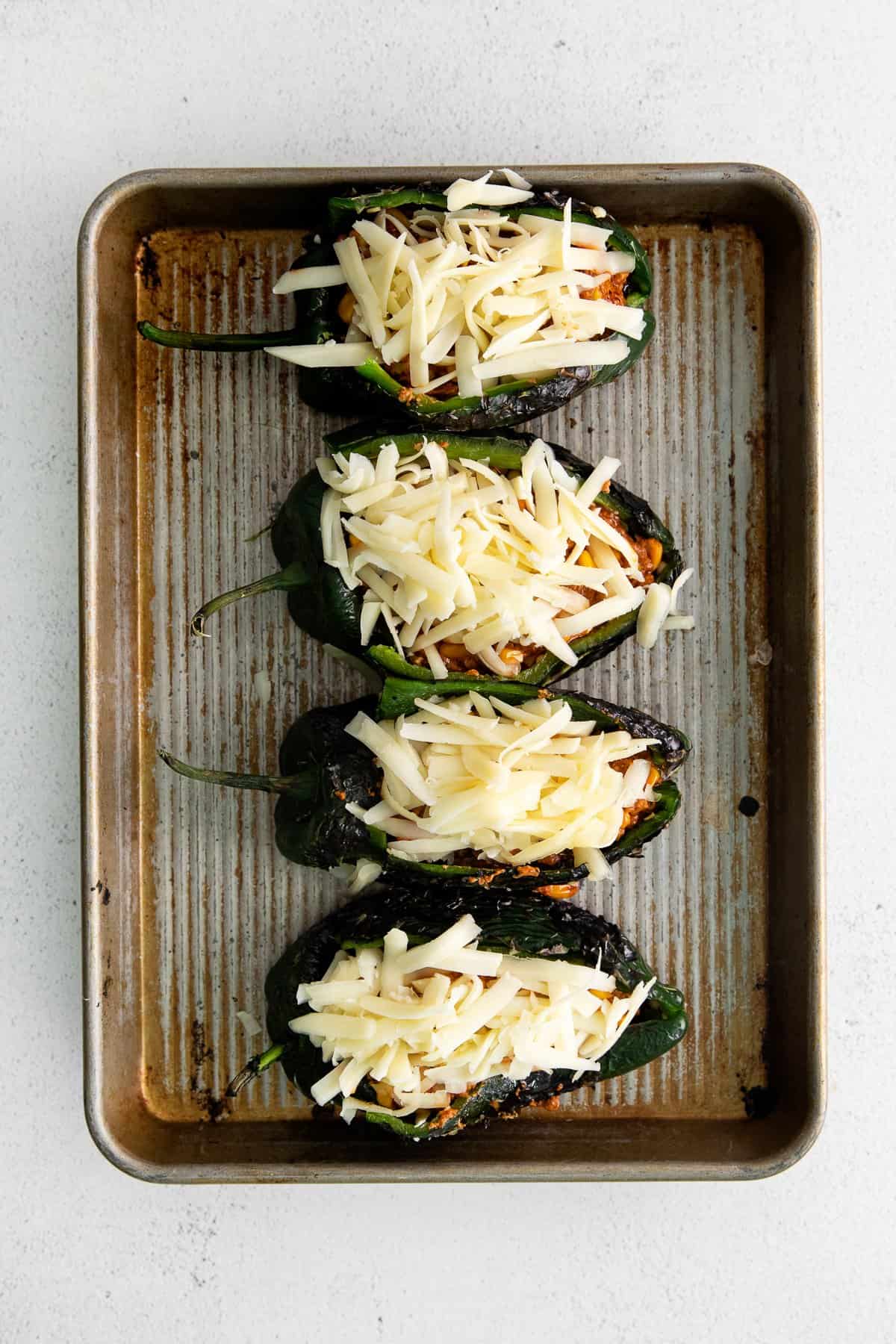 Stuffed poblano peppers topped with shredded cheese. 