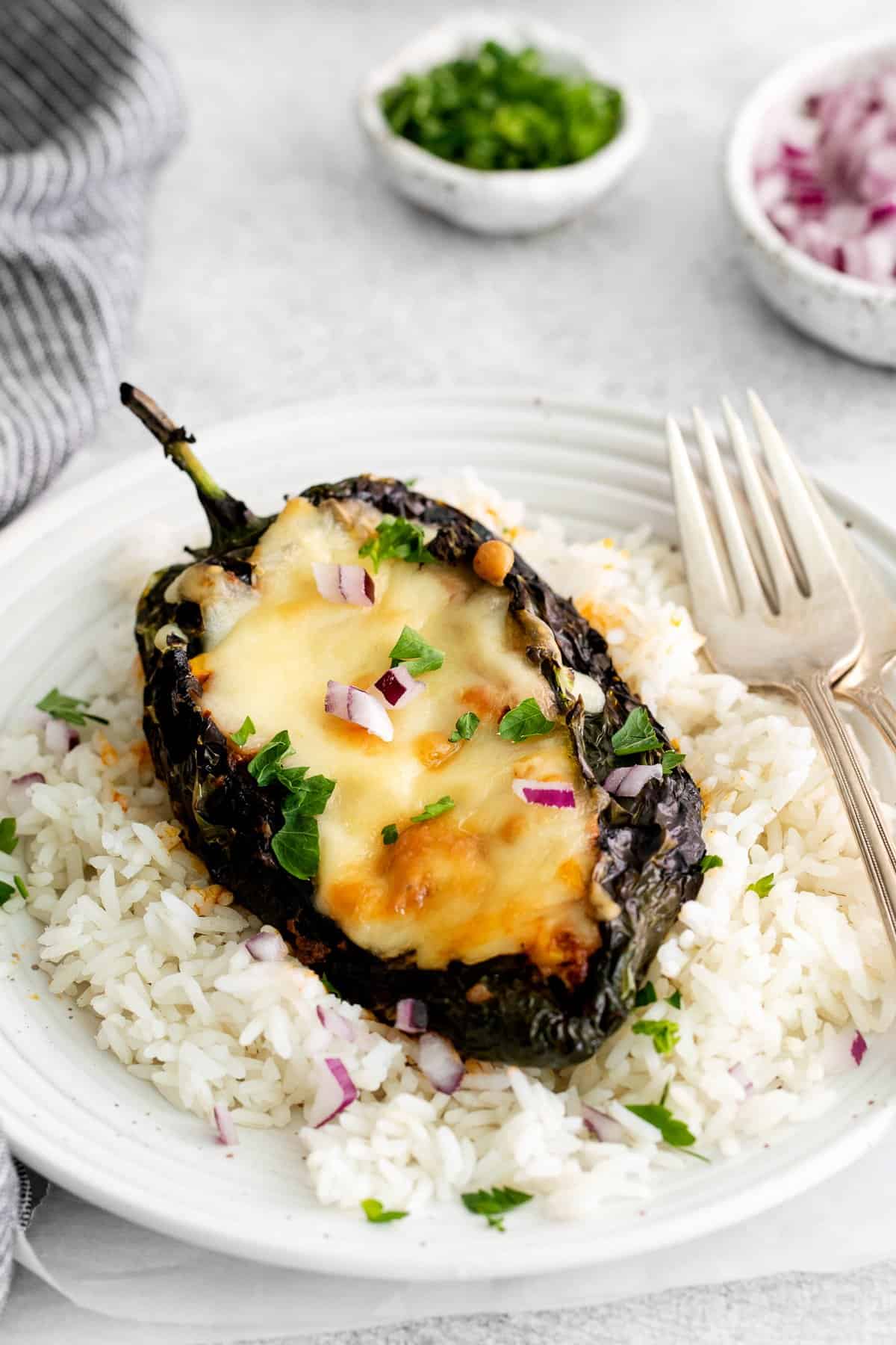 A stuffed poblano pepper on top of a bed of rice. 