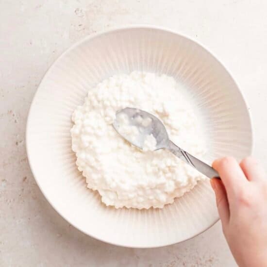 a person pouring a spoonful of rice into a bowl.