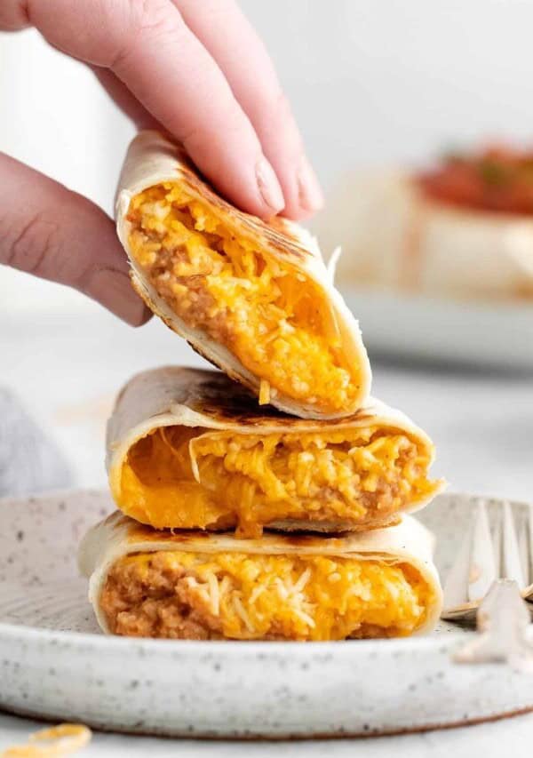 a hand picking up a bean and cheese burrito
