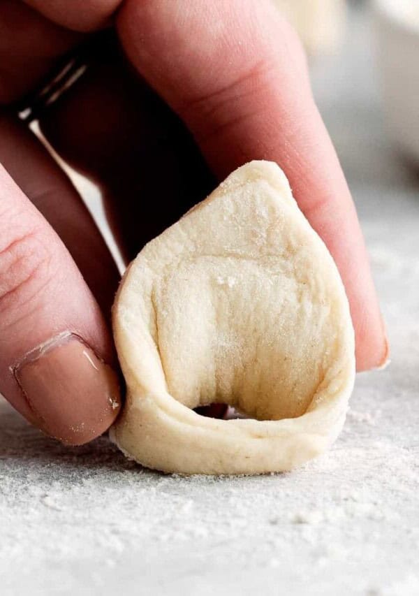 a hand holding a cheese tortellini