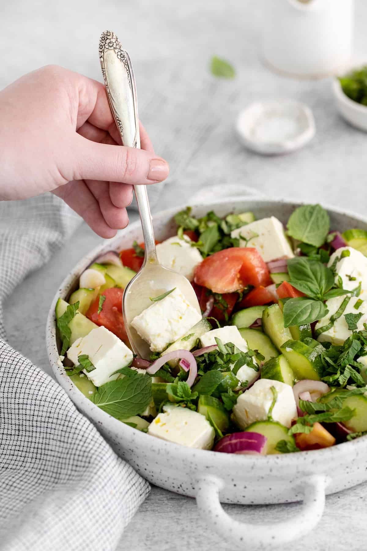 Taking a spoonful of feta out of the salad. 