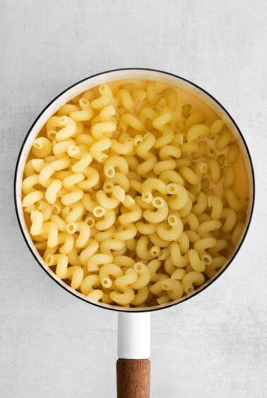 macaroni in a pan with a wooden spoon.