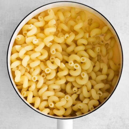 macaroni in a pan with a wooden spoon.