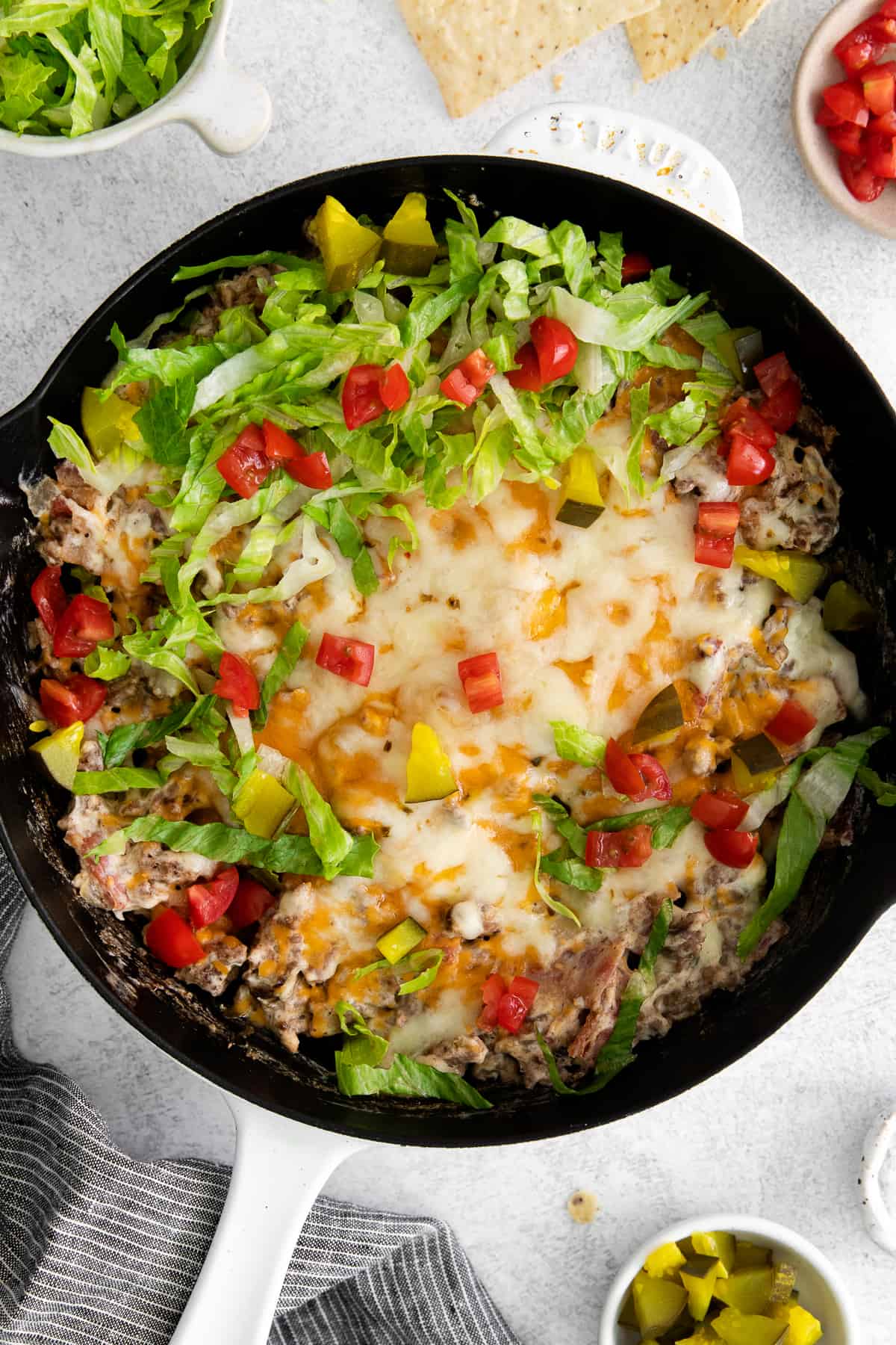 Cheeseburger dip topped with lettuce, tomatoes, and pickles. 