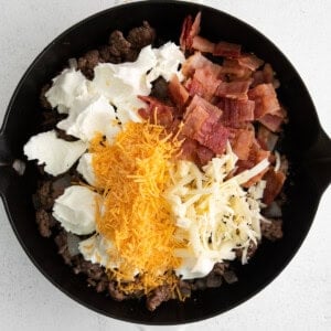 All the ingredients for cheeseburger dip in a skillet.