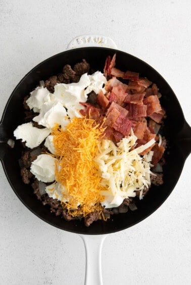 All the ingredients for cheeseburger dip in a skillet.