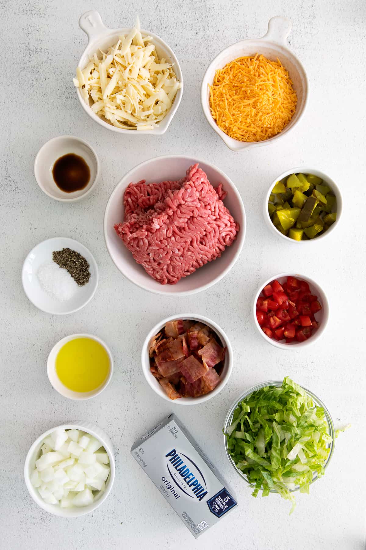 Ingredients for cheeseburger dip in small bowls. 