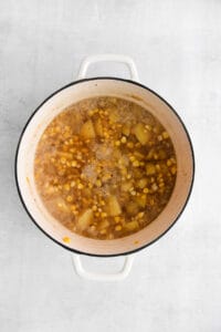 a pot of soup with beans and corn on a white background.