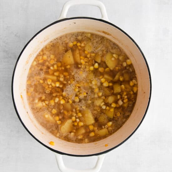 a pot of soup with beans and corn on a white background.