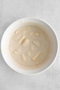 a bowl of white soup on a white surface.