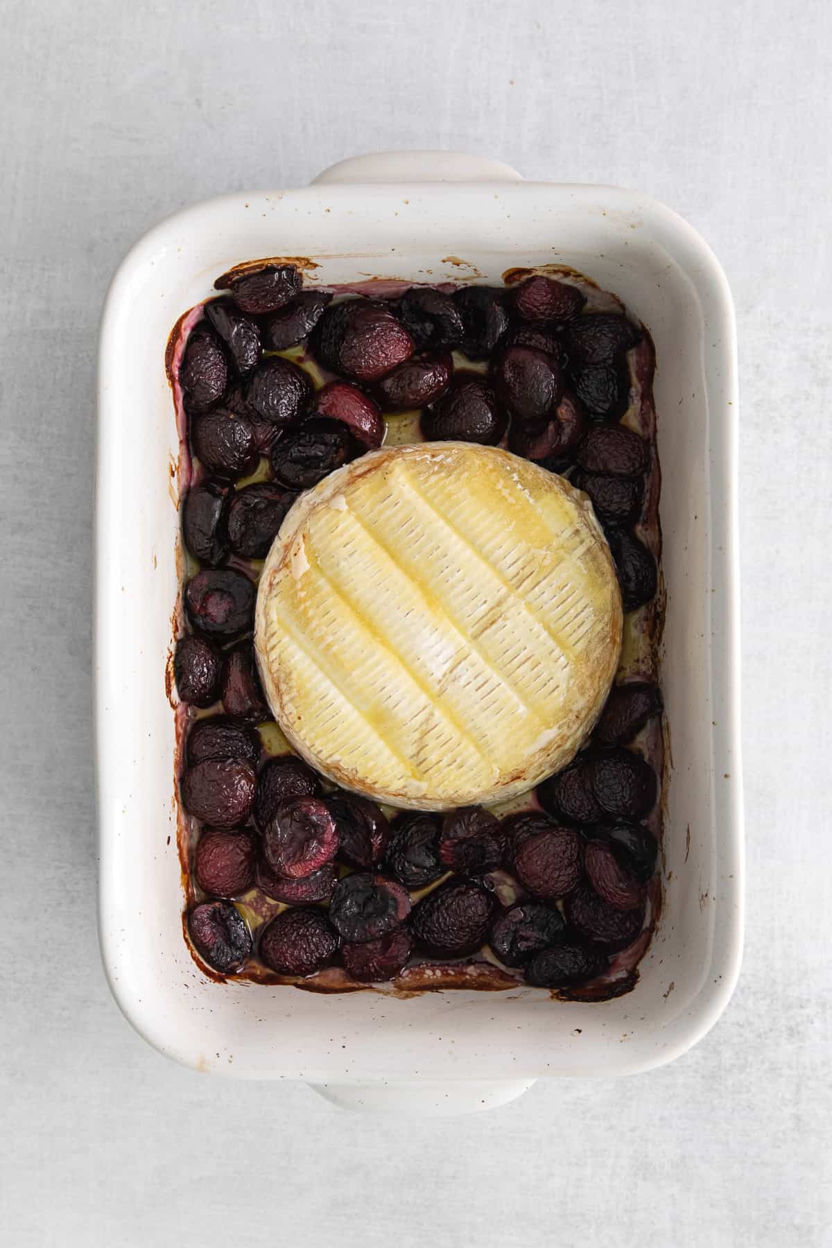 Grilled brie cheese and cherries in a baking dish.