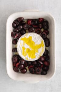a baking dish filled with cherries and a dollop of creme fraiche.