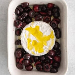 a baking dish filled with cherries and a dollop of creme fraiche.