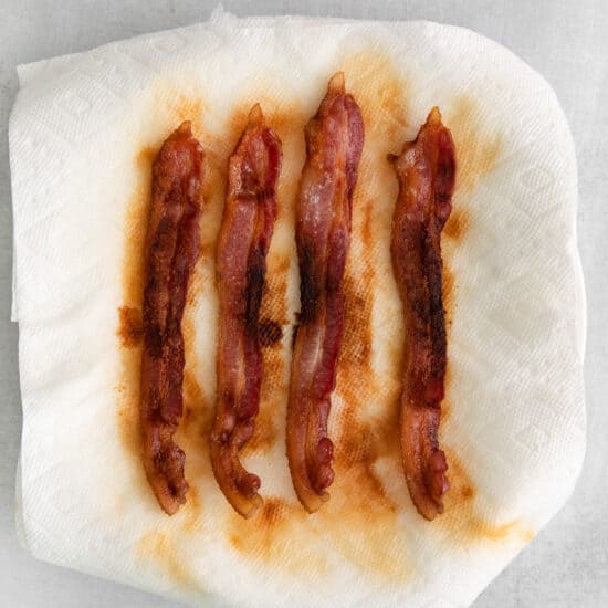 bacon wrapped in paper on a white surface.
