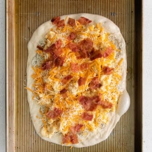 mac and cheese pizza on baking sheet.