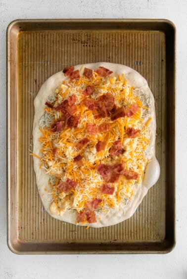 mac and cheese pizza on baking sheet.