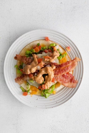 a plate with bacon, lettuce and tomatoes on it.