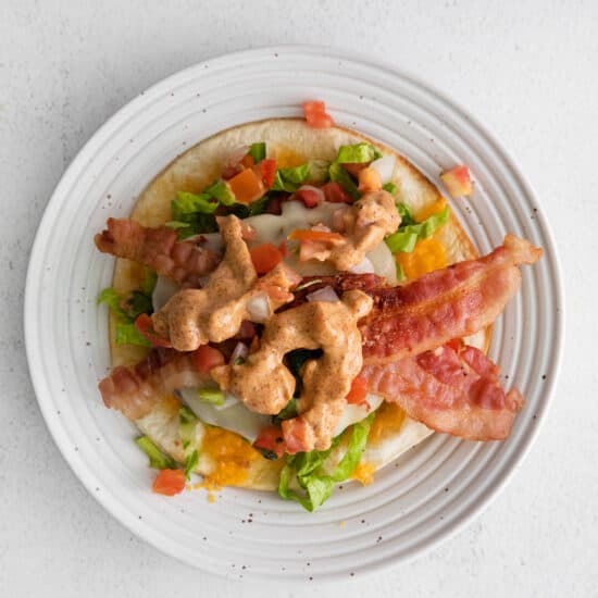 a plate with bacon, lettuce and tomatoes on it.