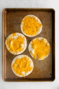 four cheesy tortillas on a baking sheet.