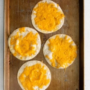 four cheesy tortillas on a baking sheet.